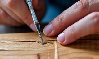 Expert repairing damaged veneer on a wooden surface.